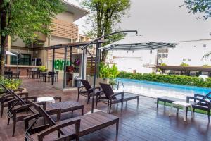 un patio con mesas y sillas junto a una piscina en Romyen Garden Place en Nakhon Ratchasima