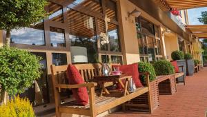 - une rangée de bancs avec des oreillers rouges sur la terrasse dans l'établissement Hotel Wegner - T h e culinary art hotel, à Hanovre