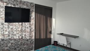 a room with a television on a stone wall at Hotel Rosales Plaza in Manizales