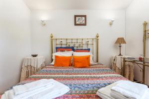 カバナス・デ・タビラにあるTypical Algarvian Family Homeのベッドルーム1室(オレンジ色の枕が付いたベッド1台付)