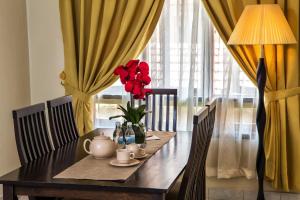 a dining room table with a vase of red flowers on it at Kijal Permai Apartment in Kijal