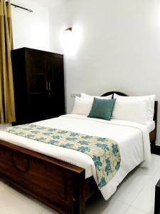a bedroom with a bed with white sheets and blue pillows at Siluni's Villa in Anuradhapura