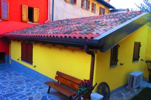 einer Bank vor einem gelben und roten Gebäude in der Unterkunft CaMé in Alzano Lombardo