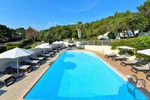 a swimming pool with lounge chairs and umbrellas at Residence Canella in Sari Solenzara