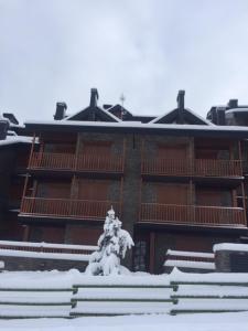a snow covered building with a statue in front of it at Apartamento frente Pistas de Esquí La Molina in La Molina +12 photos