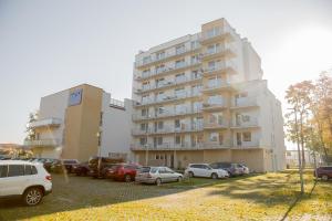 a large building with cars parked in a parking lot at Mielno Holiday Apartments in Mielno