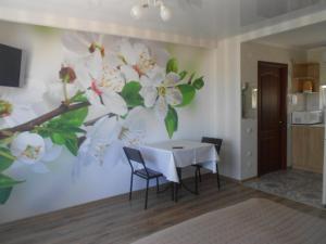 uma sala de jantar com uma mesa branca e flores na parede em квартира-студия в г. Кропивницком (Кировограде) em Kirovohrad