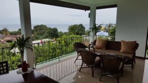 a porch with a couch and chairs on a balcony at Samui Grand Rock in Lamai