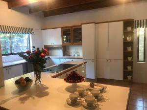 a kitchen with white cabinets and a table with flowers on it at At Home in Mostertsdrift in Stellenbosch +8 photos