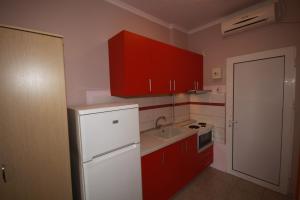 a kitchen with red cabinets and a white refrigerator at ZEPHYROS ROOMS in Ormos Panagias +60 photos