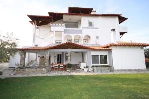a large white house with a green lawn at ZEPHYROS ROOMS in Ormos Panagias