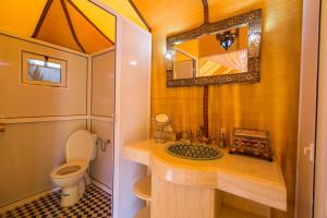 a bathroom with a toilet and a sink with a mirror at Sahara Sky Luxury Camp in Merzouga