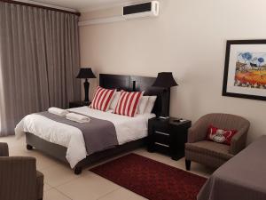 1 dormitorio con 1 cama y 1 silla en Presidensie Guest Rooms, en Potchefstroom