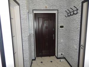 a hallway with a brown door and a brick wall at Ukrainska Apartment in Irpin