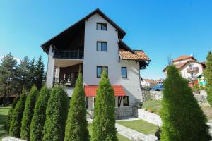 ein weißes Haus mit einem schwarzen Dach und Bäumen in der Unterkunft Apartments Vila Knez in Zlatibor