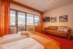 a bedroom with a bed and a couch and a window at Residence Tempele in San Candido