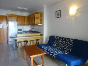 sala de estar con sofá azul y cocina en turquesa, en La Pineda