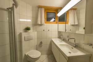 uma casa de banho branca com um lavatório e um WC em Haus Belvédère em Arosa