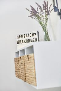 une table blanche avec un vase de fleurs et un signe qui lit herz dans l'établissement Glücksferien- Gänseblümchen, à Glücksburg