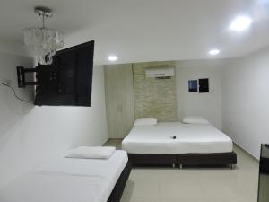 um quarto com 2 camas e uma televisão de ecrã plano em Apartahotel Dorado Rodadero em Santa Marta