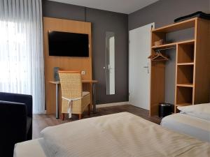 a bedroom with a bed and a desk and a television at Hotel & Restaurant Hüllen in Barweiler