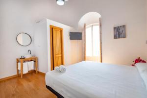 a bedroom with a large white bed and a mirror at Bekkeh in Vejer de la Frontera