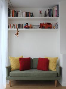 a green couch with red and yellow pillows in a room at Bright and Elegant 2 Bedroom Flat, near Notting Hill in London