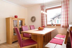 a dining room with a wooden table and pink chairs at Ferienwohnungen Alpentraum - freiSicht in Fischen