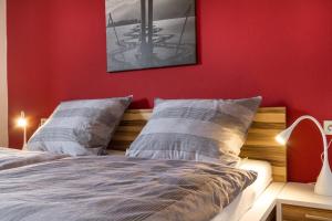 a bedroom with a red wall and a bed with pillows at Ferienwohnungen Alpentraum - freiSicht in Fischen