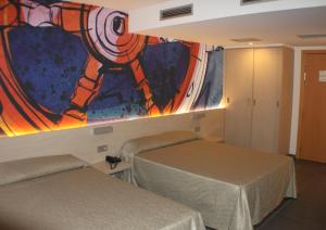 サンタ・スサナにあるHotel Rivieraの壁に絵画が飾られた部屋のベッド2台