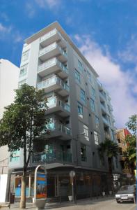 a tall white building with a tree in front of it at Hotel Pujol in Las Palmas de Gran Canaria