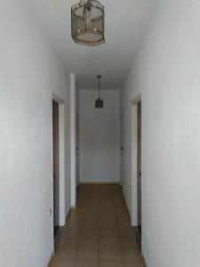 un couloir aux murs blancs et un plafond avec un lustre dans l'établissement SAM΄S ROOMS, à Corfou