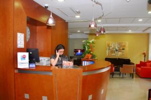 a woman sitting at a counter talking on a cell phone at Hotel Pujol in Las Palmas de Gran Canaria