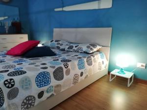 ein Schlafzimmer mit einem Bett mit Kissen und einer Lampe in der Unterkunft Sky Blue Dreams Holiday Home in Catania