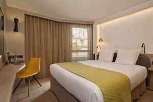 a hotel room with a large bed and a yellow chair at Auteuil Tour Eiffel in Paris