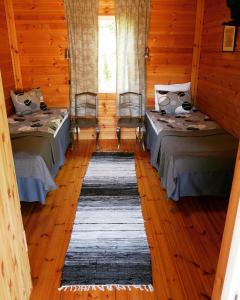 two beds in a room with wooden floors at Guesthouse Miekkala in Lappeenranta