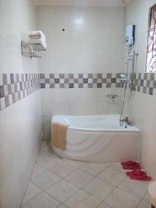 uma banheira branca na casa de banho com uma janela em Greens Guest Homes em Mutungo