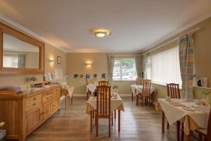 a dining room with tables and chairs and a mirror at Fair Winds Guest House in Brixham
