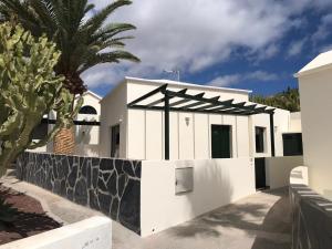 a white house with a fence and a palm tree at Bungalow Nueva York in Costa Teguise