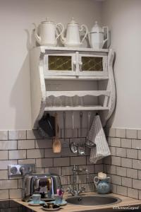 a kitchen with a sink and a shelf with pots and pans at Demeure Terrisse La Maison in Marseillan