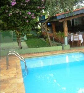 a large blue swimming pool in a yard with a table at Pousada Caminhos de São Pedro in São Pedro
