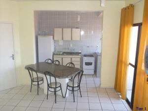 a kitchen with a table and chairs and a refrigerator at Pousada Ilhas Gregas in Florianópolis
