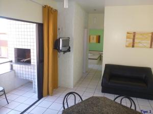een woonkamer met een bank en een tv bij Pousada Ilhas Gregas in Florianópolis