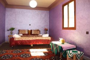 1 dormitorio con paredes de color púrpura, 1 cama y 1 mesa en Dar Imperial, en Imlil