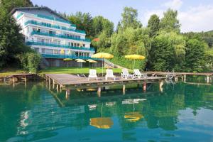 eine Anlegestelle mit Stühlen und Sonnenschirmen sowie ein Gebäude in der Unterkunft Ferienhaus Rutar in Sankt Kanzian am Klopeiner See