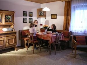 une femme et deux enfants assis à une table dans l'établissement Ferienwohnung Anna, à Sankt Kanzian