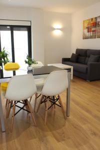 sala de estar con mesa y 2 sillas blancas en Apartamentos La Luna, en La Solana
