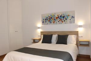 La SolanaにあるApartamentos La Lunaのベッドルーム1室(ベッド1台付)が備わります。壁には絵画が飾られています。