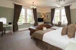a bedroom with a large bed with a couch and chairs at Three Ways House Hotel in Chipping Campden