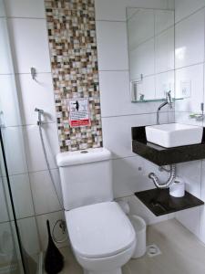 a white toilet sitting next to a white sink at Pousada do Pinheiro in Camburi